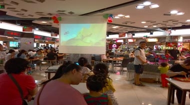 家长陪伴孩子在潍坊银座美食广场观看动画片